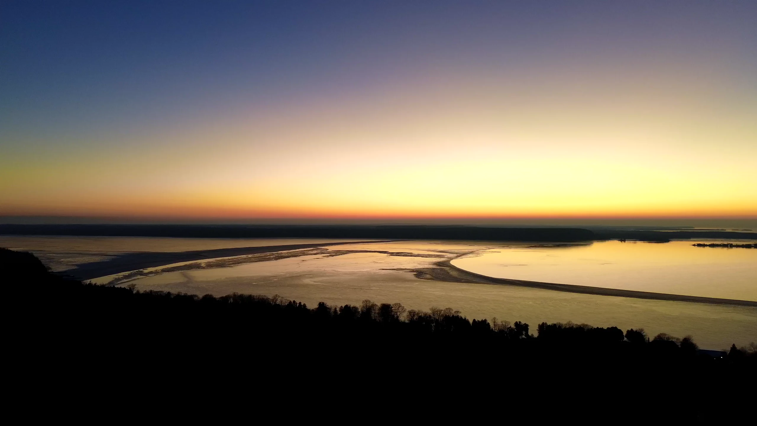 Golden sunrise reflected across a broad bay from an aerial viewpoint